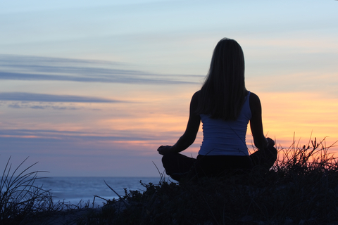 A woman mediating by the beach.